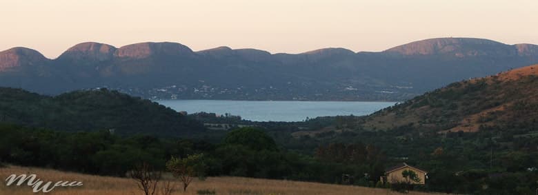 View across the Hartbeespoort Dam towards the Magaliesberg mountains at dusk